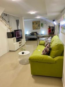 un soggiorno con divano verde e TV di BADAROSA 2 House10min to BARCELONCity&NearTo BEACH a Badalona