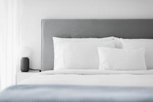 a bed with white sheets and pillows next to a window at White Innk city center apartment in Trnava