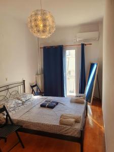 een slaapkamer met een bed met blauwe gordijnen en een kroonluchter bij Success's Apartment in Athene