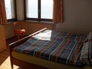 a bedroom with a bed and a chair and windows at Santa Maria Ferienwohnung in Ronco sopra Ascona