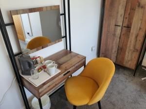 een kamer met een tafel, gele stoelen en een spiegel bij North Cambridge Guesthouse by Payman Club in Cambridge