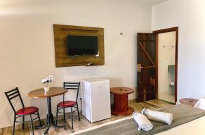 um quarto com uma pequena mesa e uma televisão na parede em Brisa do Lago Pousada em Capitólio