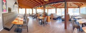 ein Restaurant mit Holztischen, Stühlen und Fenstern in der Unterkunft HIL - Hotel im Lus Schopfheim in Schopfheim