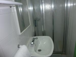 a white bathroom with a shower and a sink at Pensión Fonda Vilalta in Ribes de Freser