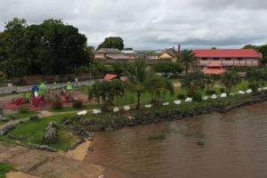 a body of water next to a river with a building at Maison dans le quartier historique de St Laurent Résidence Colibri in Saint-Laurent du Maroni