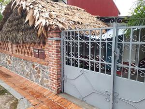 a gate to a brick building with a thatch roof at Maison dans le quartier historique de St Laurent Résidence Colibri in Saint-Laurent du Maroni