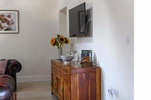 a living room with a wooden cabinet with a tv on it at The Barn @ Laurel Farm in Shotteswell