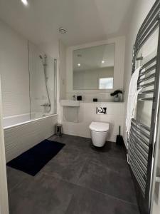 a bathroom with a toilet and a tub and a sink at Modern Suite- Bedford City centre with free gym & parking in Bedford