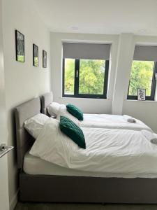 a large white bed with green pillows on it at Modern Suite- Bedford City centre with free gym & parking in Bedford