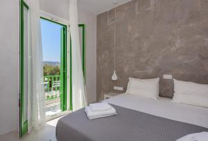 a bedroom with a bed and a large window at KLIMA BAY Beachfront Boutique Houses in Klima