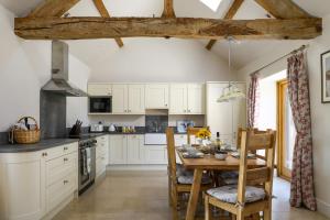 een keuken met witte kasten en een houten tafel bij The Barn @ Laurel Farm in Shotteswell
