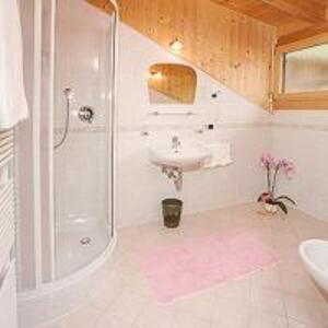 een witte badkamer met een wastafel en een douche bij Tinahof in Selva di Val Gardena