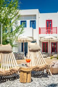 two lounge chairs and a glass of wine in front of a house at KLIMA BAY Beachfront Boutique Houses in Klima
