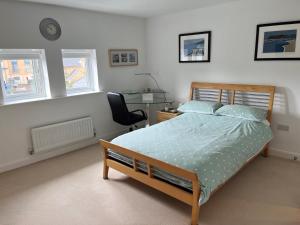 a bedroom with a bed and a desk and windows at Peterborough, Hampton Vale Lakeside En-Suite Large Double bedroom with great modern facilities in Peterborough