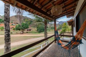 a hammock on the porch of a house with a view at Hotel Fazenda Santa Helena in Simão Pereira