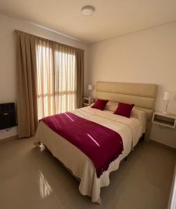 a bedroom with a large bed with red pillows at Departamento Alva in Bahía Blanca