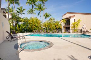 uma piscina com uma cadeira ao lado de um edifício em Country Club Villas 124 em Kailua-Kona