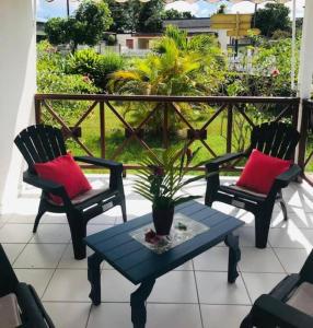 two chairs and a table with a potted plant on a porch at Villa Sous le Manguier-Anse Bertrand 5min plage in Anse-Bertrand