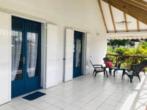 un porche con puertas azules y sillas en una casa en Villa Sous le Manguier-Anse Bertrand 5min plage en Anse-Bertrand