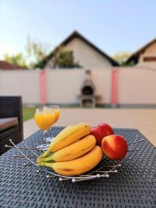 a plate of fruit on a table with a glass of orange juice at Haus mit großen Garten in Modriča