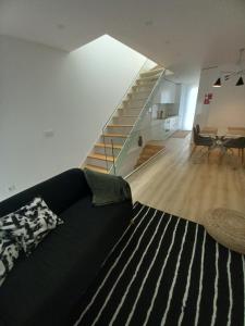 ein Wohnzimmer mit einer schwarzen Couch und einer Treppe in der Unterkunft Casa Aveiro Modern House in Aveiro + 3 Fotos
