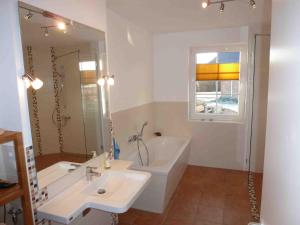 a bathroom with a tub and a sink and a bath tub at Reetdachhaus am Bodden Middelhagen in Middelhagen