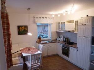 a kitchen with white cabinets and a table and a window at Reetdachhaus am Bodden Middelhagen in Middelhagen +23 photos
