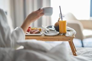 une personne au lit avec un plateau de nourriture sur une table dans l'établissement Holiday Inn Prague, an IHG Hotel, à Prague