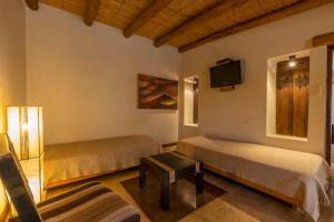 una camera con due letti e una TV a parete di Al Sereno Hotel y Spa a Tilcara