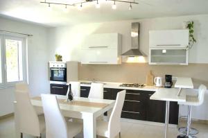 a white kitchen with a table and white chairs at Apartment Olivia in Šmrika