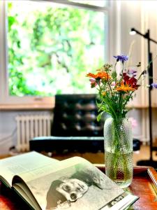 a vase of flowers and a book on a table at La bellétage by Agelandkaai be with Free Parking in Ghent