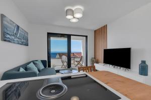 ein Wohnzimmer mit einem Tisch, einem Sofa und einem TV in der Unterkunft Apartment Nizza in Makarska