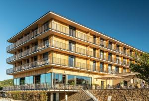 un edificio de apartamentos con balcones, mesas y sombrillas en PAPA RHEIN - Hotel & Spa en Bingen am Rhein