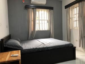 a bed in a bedroom with a desk and a window at Villa Damas in Lomé