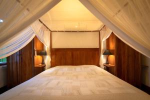 a bedroom with a large bed with wooden walls at Casa Duas Suítes no Centro Histórico in Paraty