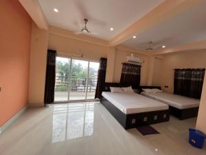 a bedroom with two beds and a large window at Hotel Krishna Paradise in Deoghar