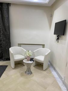 2 weiße Stühle und ein TV in einem Zimmer in der Unterkunft Villa avec piscine in Triffa