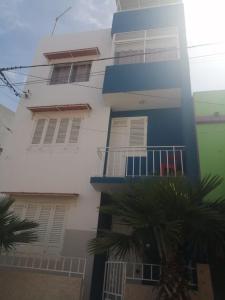 a tall white building with windows and palm trees at Apartamento Casa hollanda in Mindelo