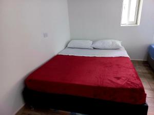 a bed in a room with a red and white blanket at Finca Mirador del Cielo Tena, Cundinamarca in Tena