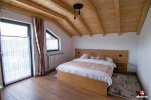 - une chambre avec un grand lit et une grande fenêtre dans l'établissement Liniștea Codrului, à Borşa
