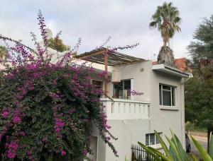 una casa blanca con flores púrpuras delante de ella en Budler Stay, 3 Bedroom, Self Catering apartment en Upington