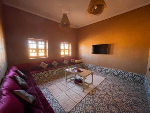 sala de estar con sofá púrpura y mesa en Tigmi Timhar, 