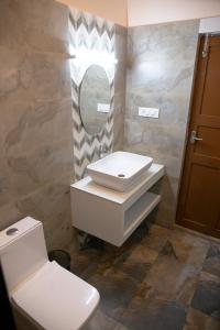 a bathroom with a sink and a toilet and a mirror at Marari Edens in Mararikulam