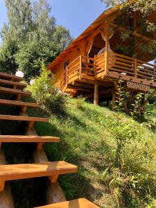 a wooden cabin with stairs leading up to it at Domeniul Horj Casa din Stejar Moisei in Moisei