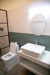 a bathroom with a sink and a toilet and a mirror at Marari Edens in Mararikulam