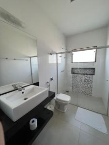 La salle de bains blanche est pourvue d'un lavabo et de toilettes. dans l'établissement Pousada Pé da Serra, à Capitólio