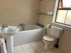 a bathroom with a tub and a toilet and a sink at Chapel Cross House in Ballinskelligs