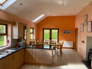 a kitchen with orange walls and a table and chairs at Chapel Cross House in Ballinskelligs