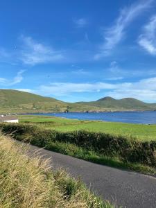 a road next to a body of water with mountains at Chapel Cross House in Ballinskelligs