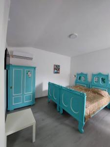 a bedroom with two blue beds and a bench at apartman Vrdničak 2 in Vrdnik